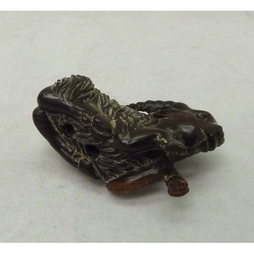 392 - A netsuke depicting a ram, signed to front leg, carved hardwood, 50mm long.