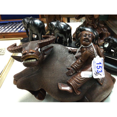 153 - A Chinese carved wood water buffalo together with two similar carved figures and a set of carved ele... 