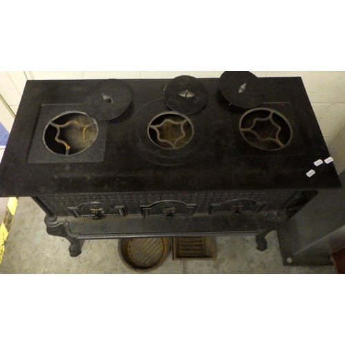 626 - A decorated metal stove with three ring top on cabriole legs, left ring damaged, 87cm wide together ... 