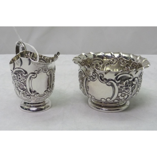 424 - A Victorian repousse decorated silver cream jug and matching sugar bowl, Chester 1900.  Cream jug 65... 