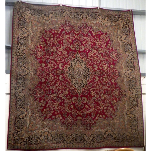 938 - A large machine made red ground carpet, 356cm x 316cm, wear