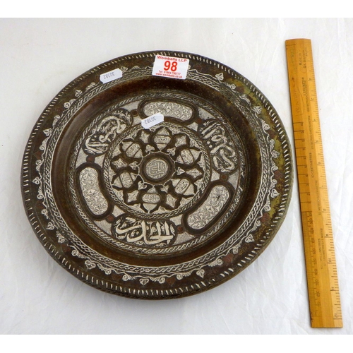 98 - A plate bearing Islamic script design etc, brass and white metal. 27.5cm