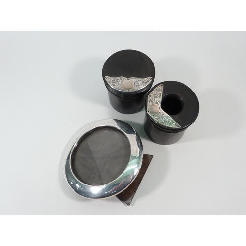 3 - Two ebony dressing table pots having applied silver panels; a circular photograph frame, 100mm outsi... 