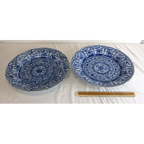 551 - A near pair of Chinese blue and white chargers, profusely decorated with floral panel scheme, the ba... 