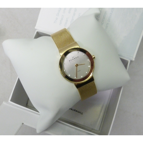 122 - A Skagen ladies gold tone wristwatch on a mesh strap, boxed; a Black Forest style desk blotter.