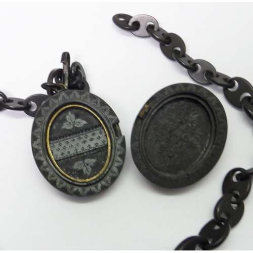 70 - A carved black stone photo locket on a similar graduated chain, a/f small breaks, chain 510mm long /... 