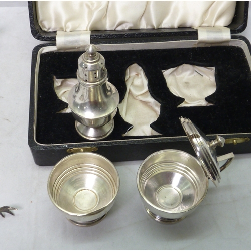 88 - A cased silver three piece condiment set, glass liners lacking; a silver boat-shaped pedestal salt, ... 