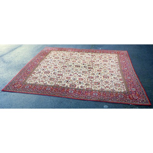 937 - A large machine made rug with beige centre and red border 275 x 272cm