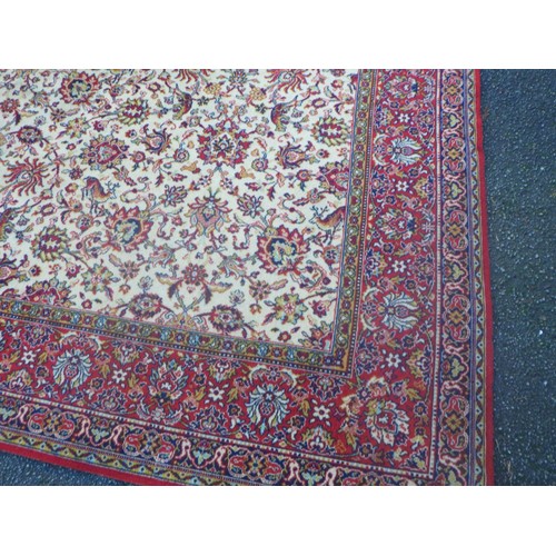 937 - A large machine made rug with beige centre and red border 275 x 272cm