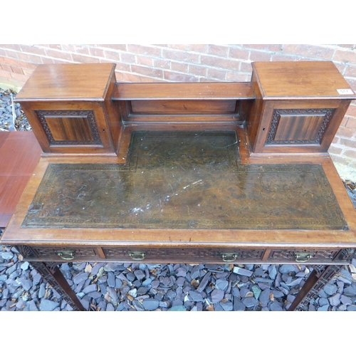 517 - An Edwardian mahogany, blind fretwork decorated writing table with leather inset top and side slides... 