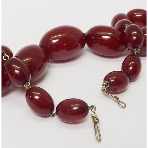 22 - A necklace of cherry coloured bakelite beads.  Largest bead  30mm long / string 435mm long.
791967