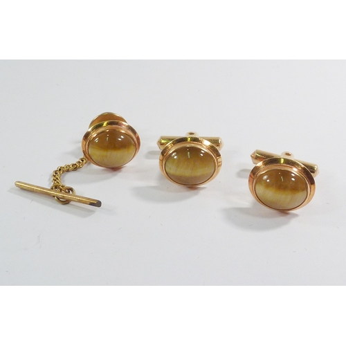 16 - A pair of cufflinks and a matching tie stud, yellow metal marked 18kt set with tiger's eye cabochons... 