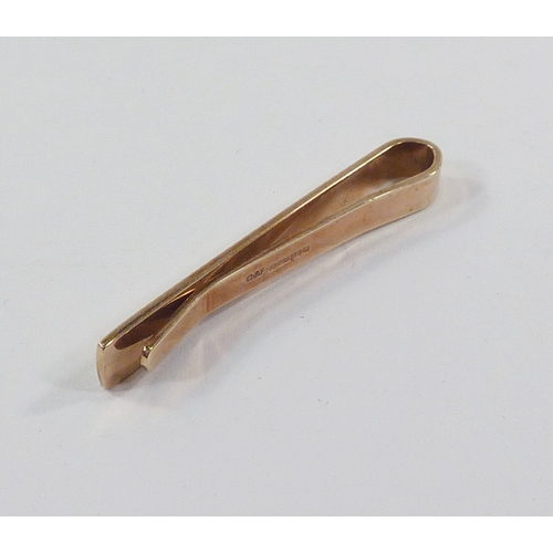 25 - A tie clip having engine turned decoration, 9ct gold.  Approximately 4gr / 44mm long.