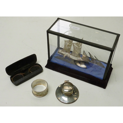 65 - A silver capstan inkwell, 70mm across base; a silver napkin ring; a white metal sailing ship etc.