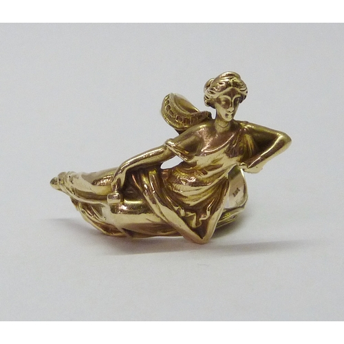 416 - A ring cast with a reclining female figure in classical influence robes, yellow metal marked 14k.  F... 