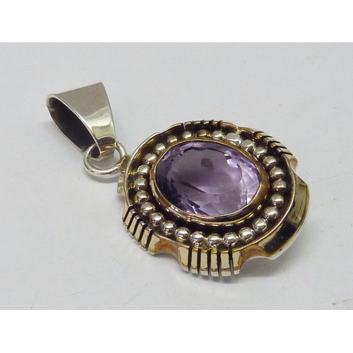 430 - A Lee Bennett Navajo pendant comprising a central synthetic amethyst in a white and yellow metal mou... 