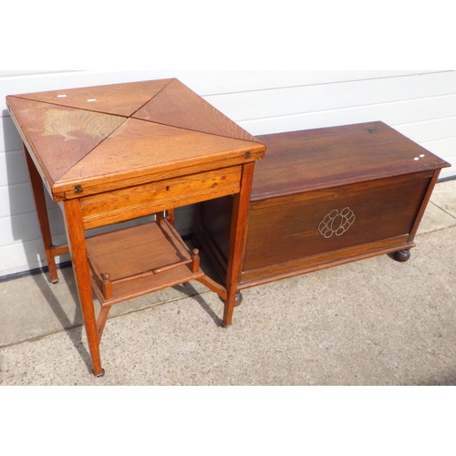 823 - An Edwardian oak envelope card table, top marked, missing handles, together with an oak/ply blanket ... 