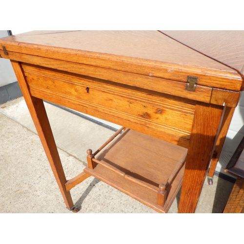 823 - An Edwardian oak envelope card table, top marked, missing handles, together with an oak/ply blanket ... 