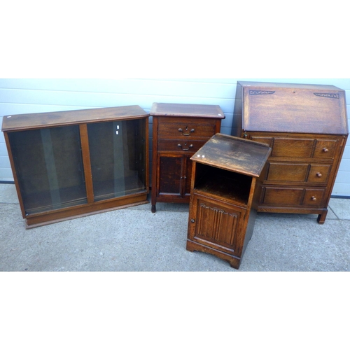 699 - An oak bureau, sliding door bookcase, linenfold bedside cabinet and another cupboard (4)