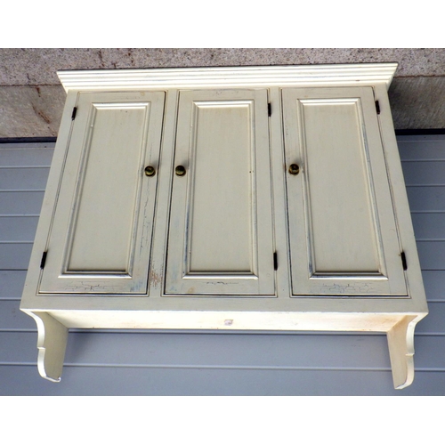 717 - A cream painted 3 door hanging cupboard, 128cm wide