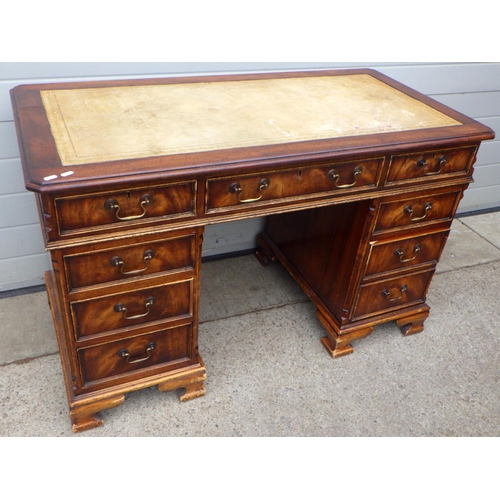 825 - A reproduction mahogany pedestal desk with leather inset top, with label Artistic Cabinets, 124cm wi... 