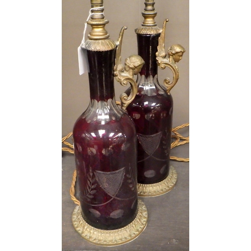 101 - A pair of red-flashed-glass bottle-based table lamps with pleated shades.