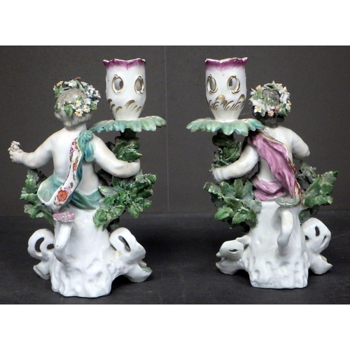 102 - A pair of floral encrusted cherub candlesticks; a taza stand having pierced basket and a lozenge sha... 