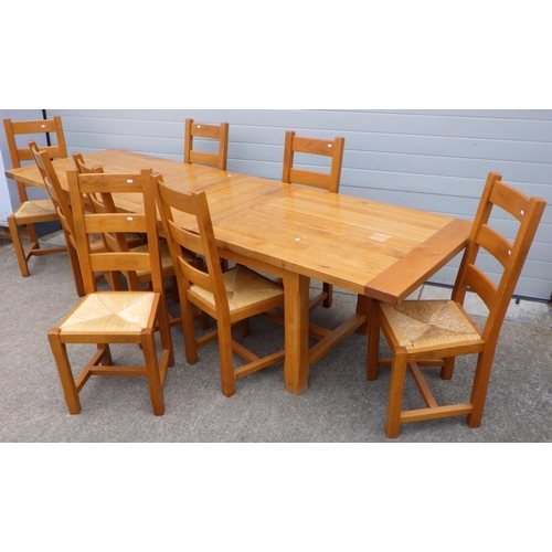 696 - A large modern oak extending dining table with 8 matching ladderback chairs 300cm x 90cm open (9)