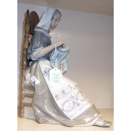 269 - A  Lladro figurine depicting a woman seated in a chair and sewing.
Af chip to base