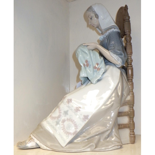 269 - A  Lladro figurine depicting a woman seated in a chair and sewing.
Af chip to base