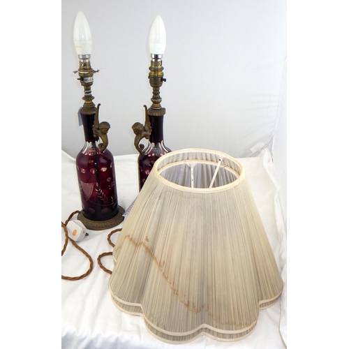 155 - A pair of red-flashed-glass bottle-based table lamps with pleated shades.