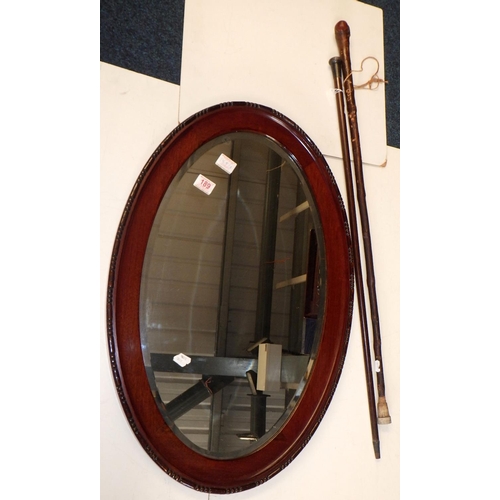 189 - A mahogany framed bevelled mirror together with two walking sticks (3)