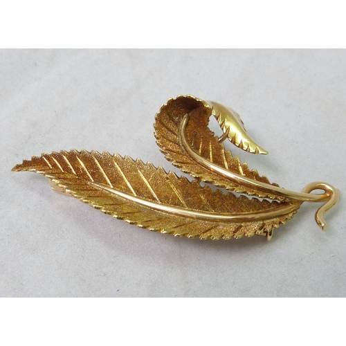 61 - A leaf-shaped brooch, yellow metal marked 750 Industria Argentina, 61mm across; a ribbon twist brooc... 