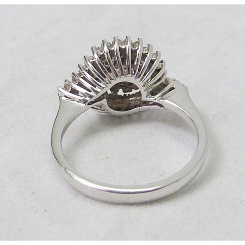 63 - A diamond cluster ring of spiral form, 18ct white gold.  Head 13mm across / central stone approximat... 