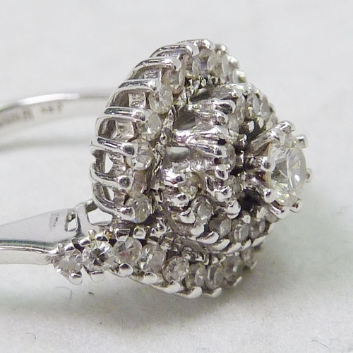 63 - A diamond cluster ring of spiral form, 18ct white gold.  Head 13mm across / central stone approximat... 