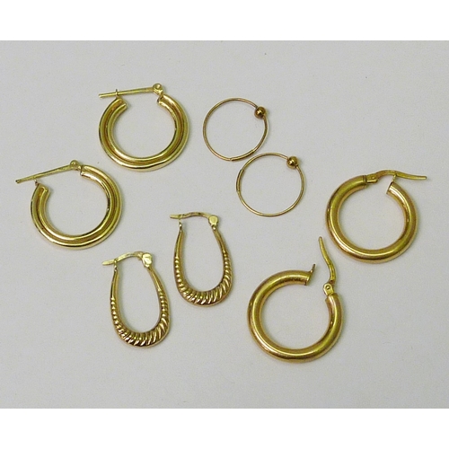 75 - Four pairs of yellow metal hoop earrings.