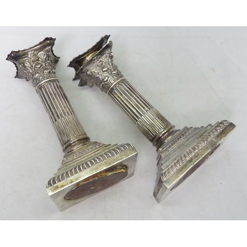 84 - Silver: a pair of Corinthian column candlesticks, 155mm tall; a silver topped claret jug, glass crac... 