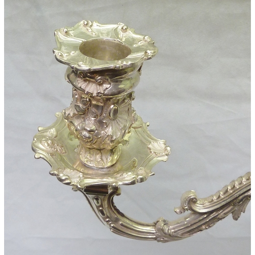 96 - A Victorian candelabra having cast and chased rococo decoration, the sconces and stem engraved with ... 