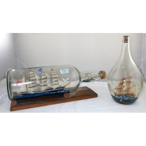 111 - A ship in a bottle with another in the neck on a wooden stand together with another ship in a bottle... 