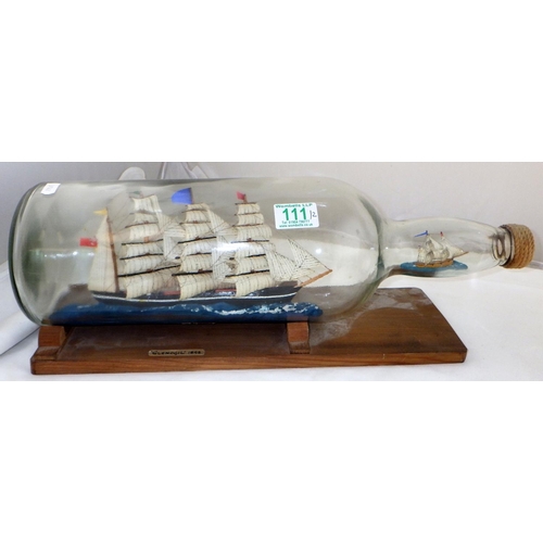 111 - A ship in a bottle with another in the neck on a wooden stand together with another ship in a bottle... 