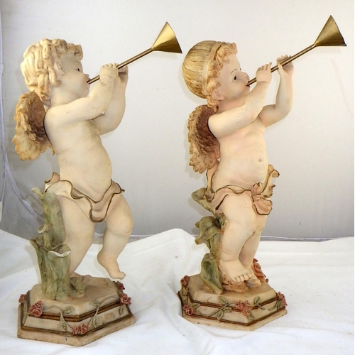 135 - A pair of cherub figures blowing horns together with a pair of 'Blackamore' figures reading