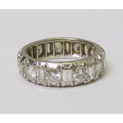 93 - A full hoop diamond eternity ring comprising eleven brilliant cut diamonds and eleven baguette cut d...