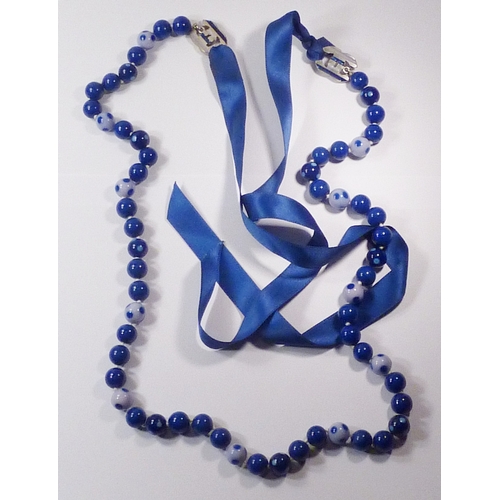 301 - A Chanel spotted glass bead necklace fastening on blue silk ribbons, beads and CC logos 700mm long, ... 