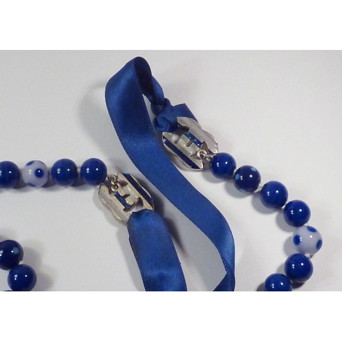 301 - A Chanel spotted glass bead necklace fastening on blue silk ribbons, beads and CC logos 700mm long, ... 