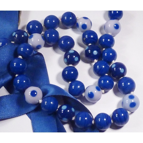 301 - A Chanel spotted glass bead necklace fastening on blue silk ribbons, beads and CC logos 700mm long, ... 