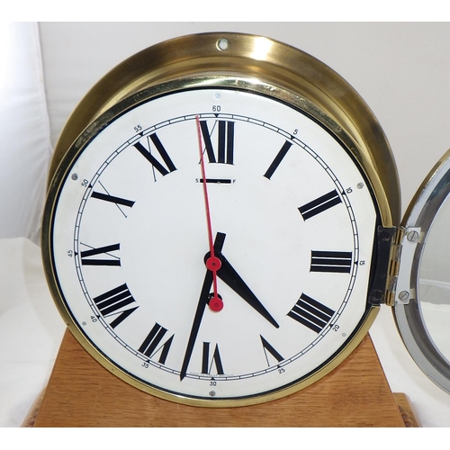 12 - A Bulkhead clock mounted on an oak stand, working