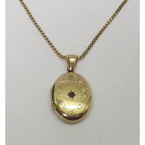 313 - A 9ct gold photo locket set with a single brilliant cut red sapphire, the whole suspended on a 9ct g... 