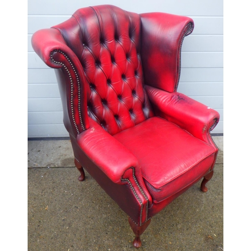 755 - A red buttoned leather wingback chair, damage