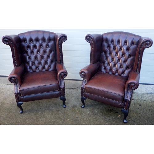 A pair of Thomas Lloyd brown leather upholstered wingback armchairs, odd mark