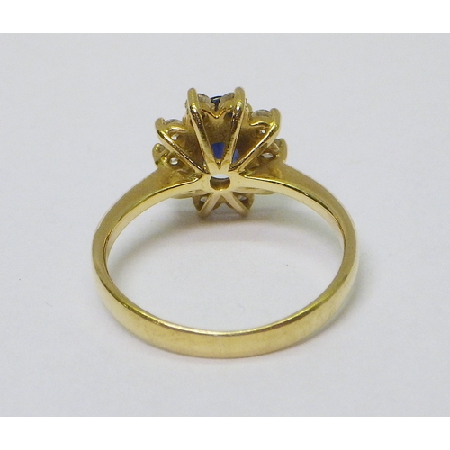 32 - A cluster ring comprising 10 brilliant cut diamonds around an oval cut sapphire, unmarked yellow met... 